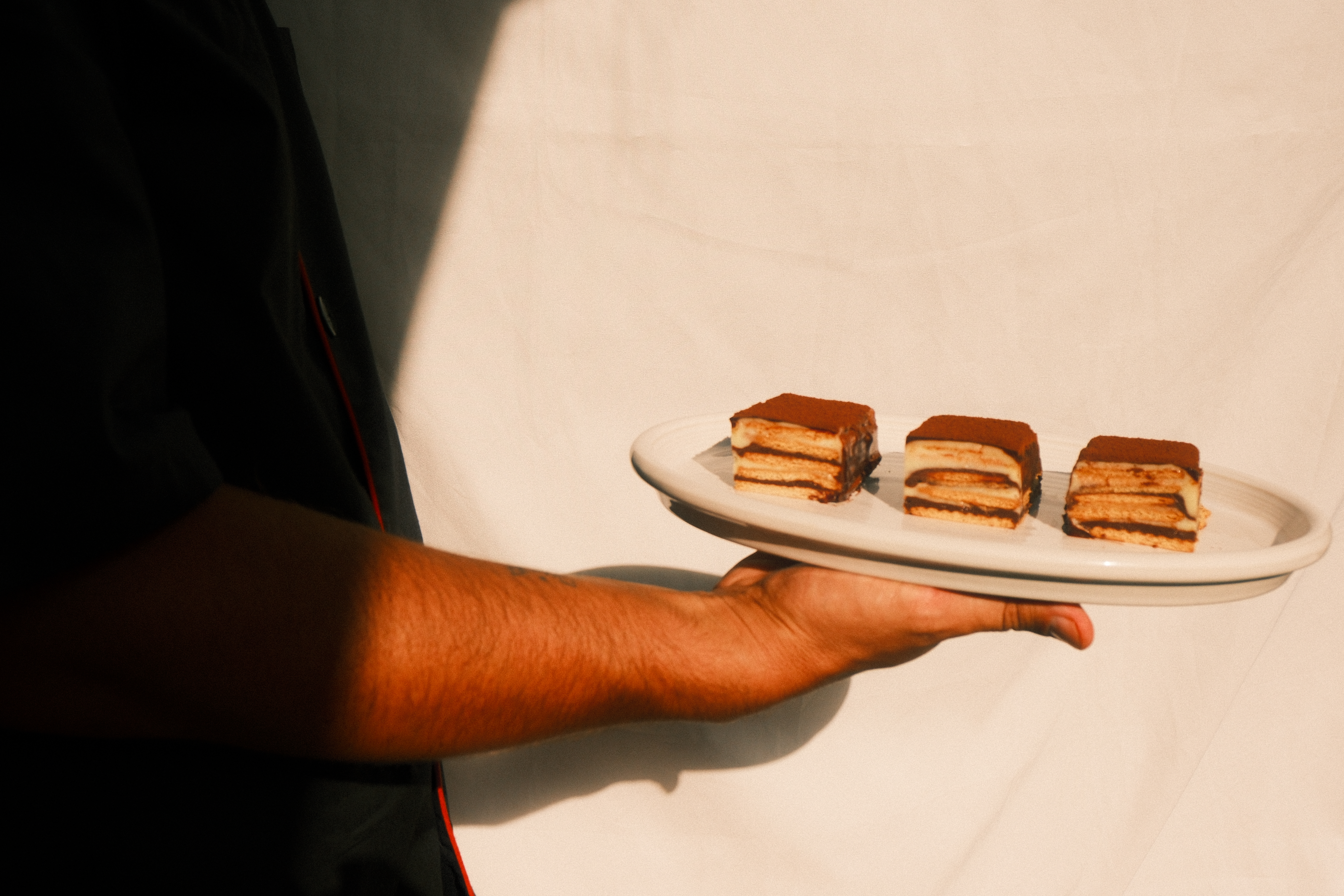 Persona sirviendo mini postres en un plato para restaurante.